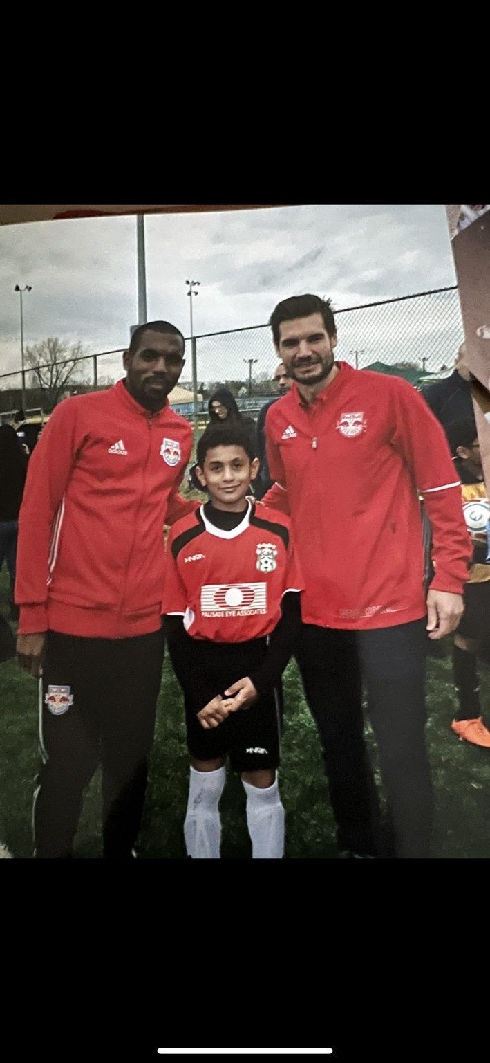 Coach Mo as a child in his red soccer uniform on the field