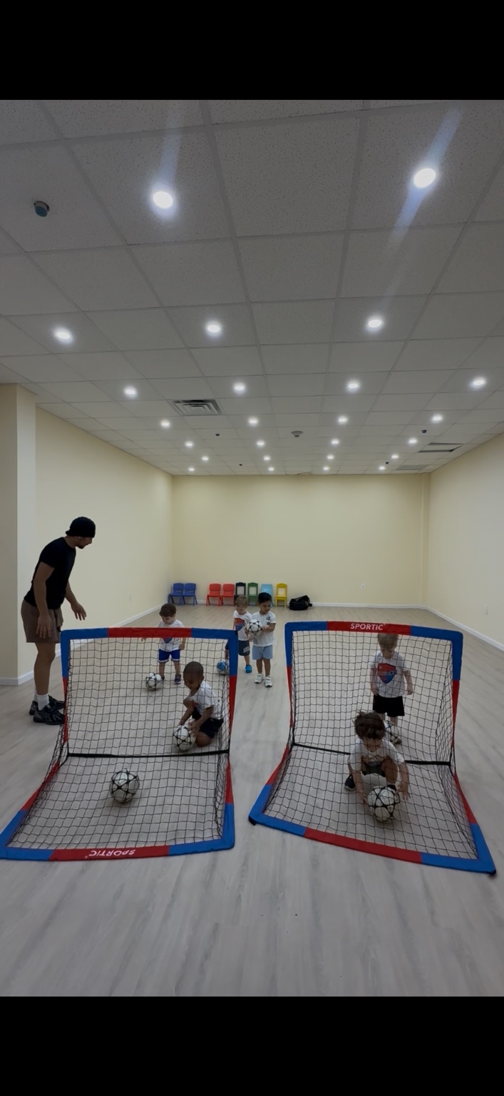 Coach Mo leading a soccer activity with children at the goals
